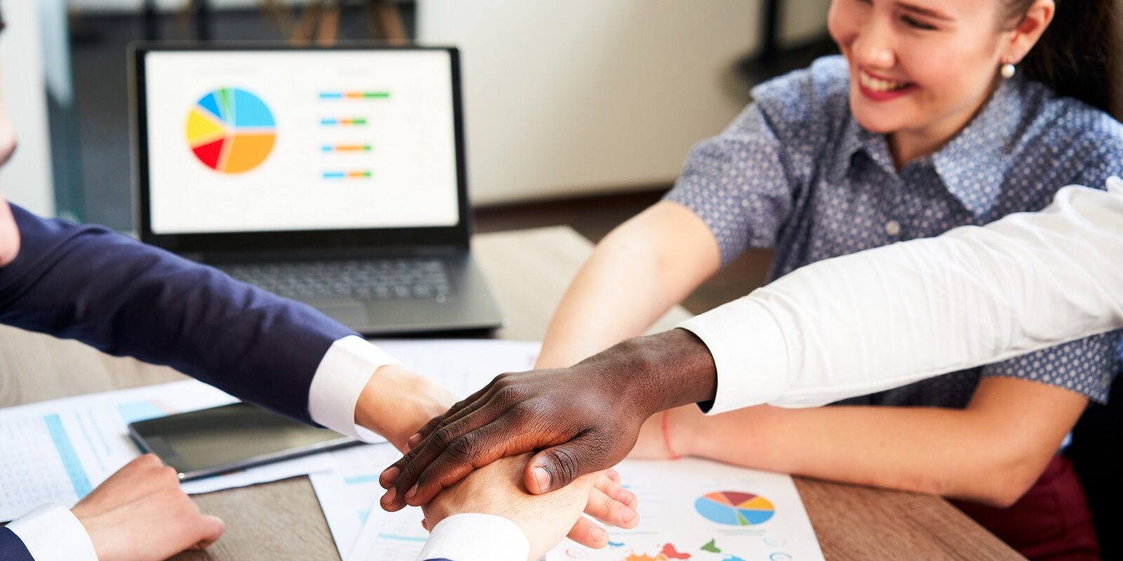 International business team showing unity with their hands stacked together in pile. Black african-american hand on top. Mixed race multiethnic group join their hands. Businessman and businesswoman.